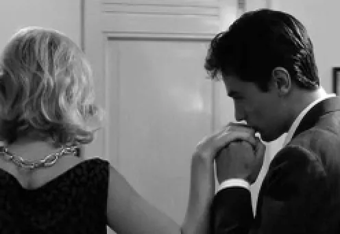 A man in a suit kissing a woman’s hand