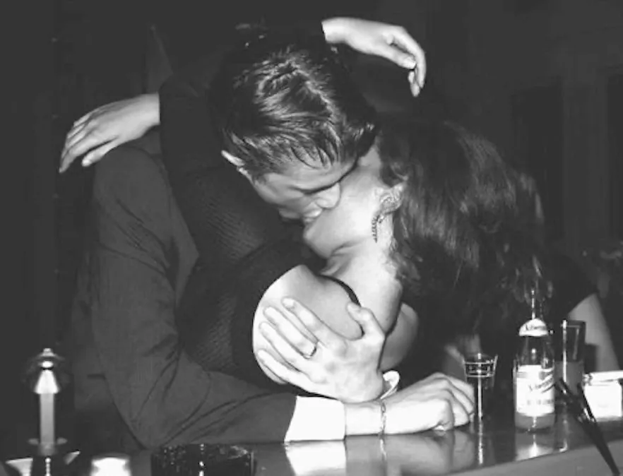 A couple kissing at a bar in black and white